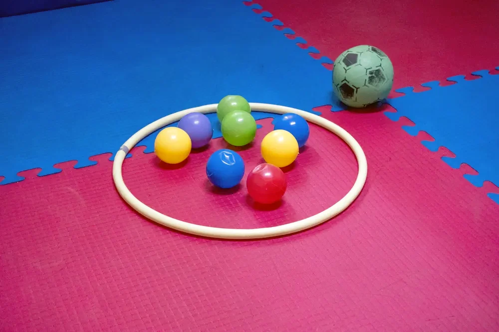 Materiales de estimulación: aro, pelotas de colores y colchoneta